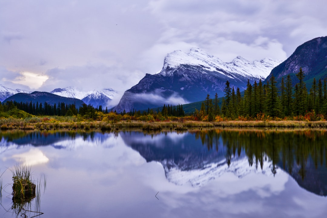 A lake surrounded by mountains and trees under a cloudy sky
