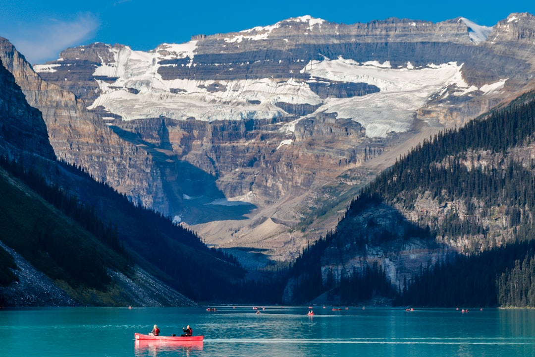 A red canoe on a vibrant turquoise lake with mountains.