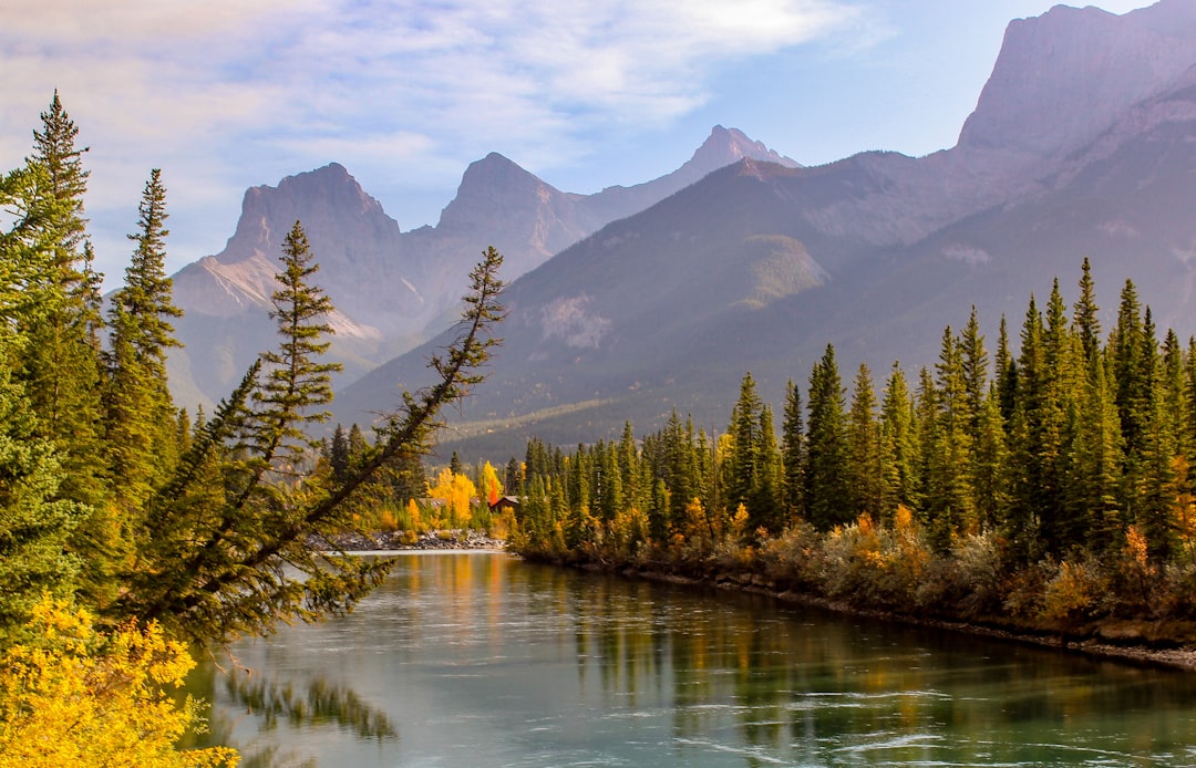 Majestic mountains overlook a river flowing through an autumn forest.