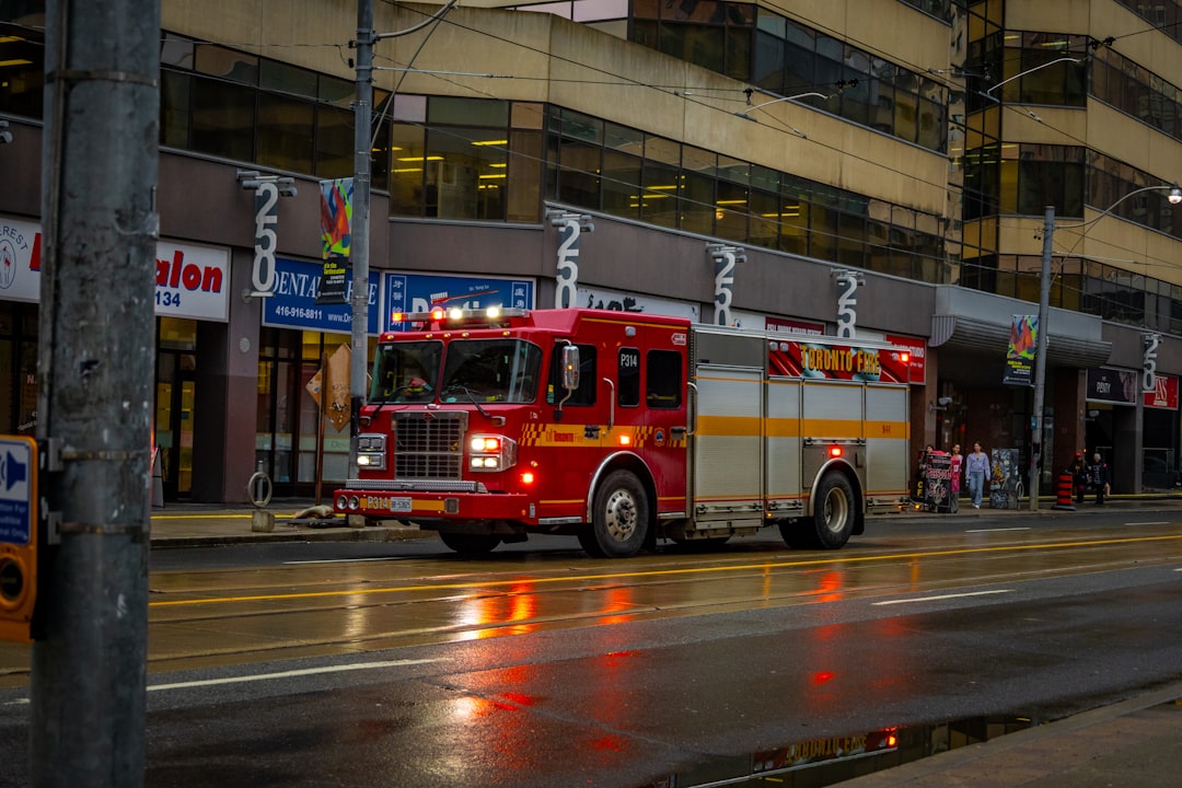 a red fire truck driving down a street next to a tall building