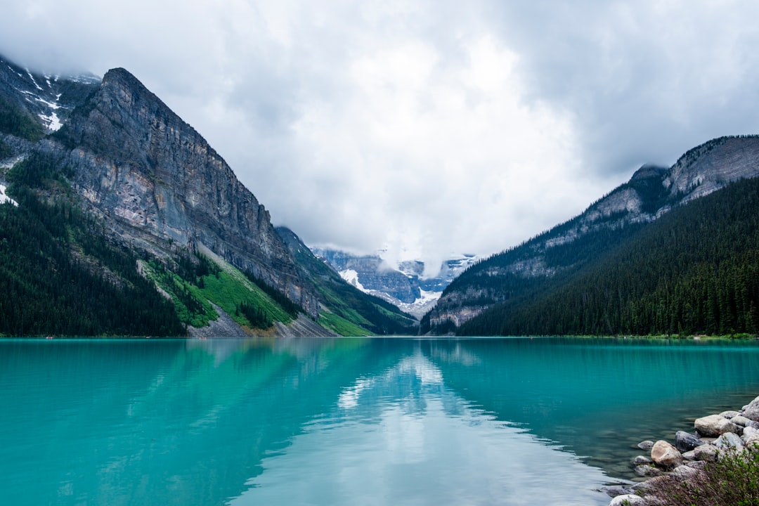 Turquoise lake reflects majestic mountains under cloudy sky
