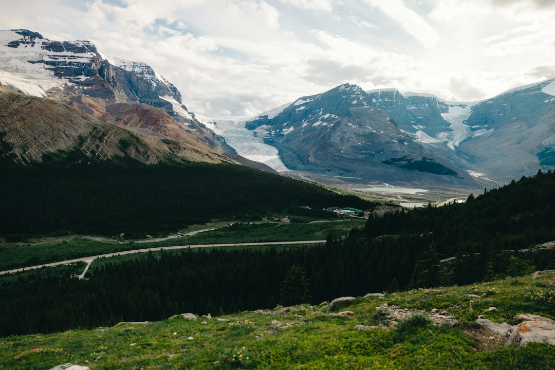 Mountains and a glacier sit under a cloudy sky