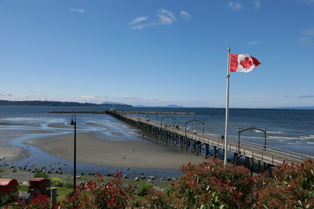 Canadian flag and a long pier over a sandy beach