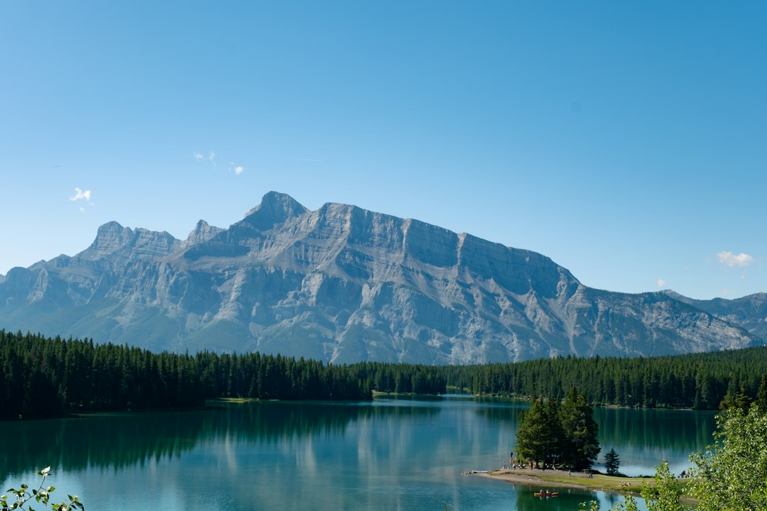 Mountain range reflected in a calm lake with pine trees