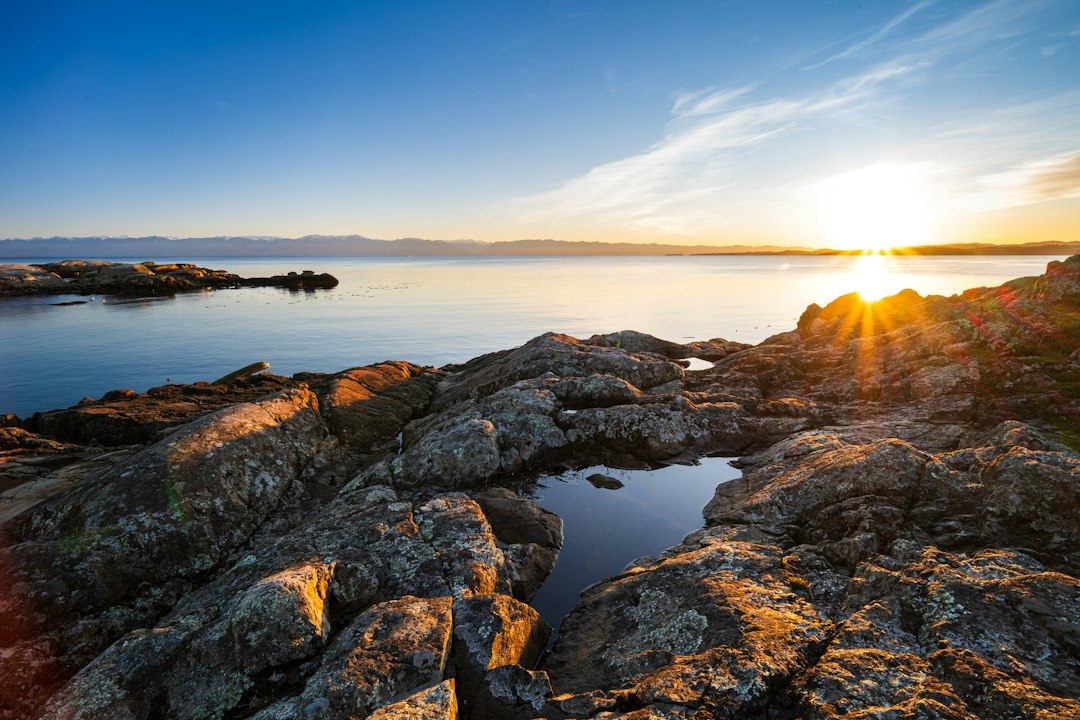 The sun is setting on the rocky shore