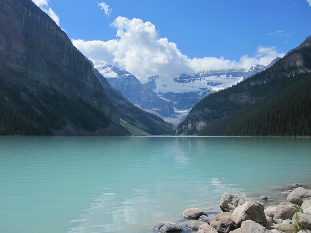 Turquoise lake surrounded by majestic mountains under a blue sky