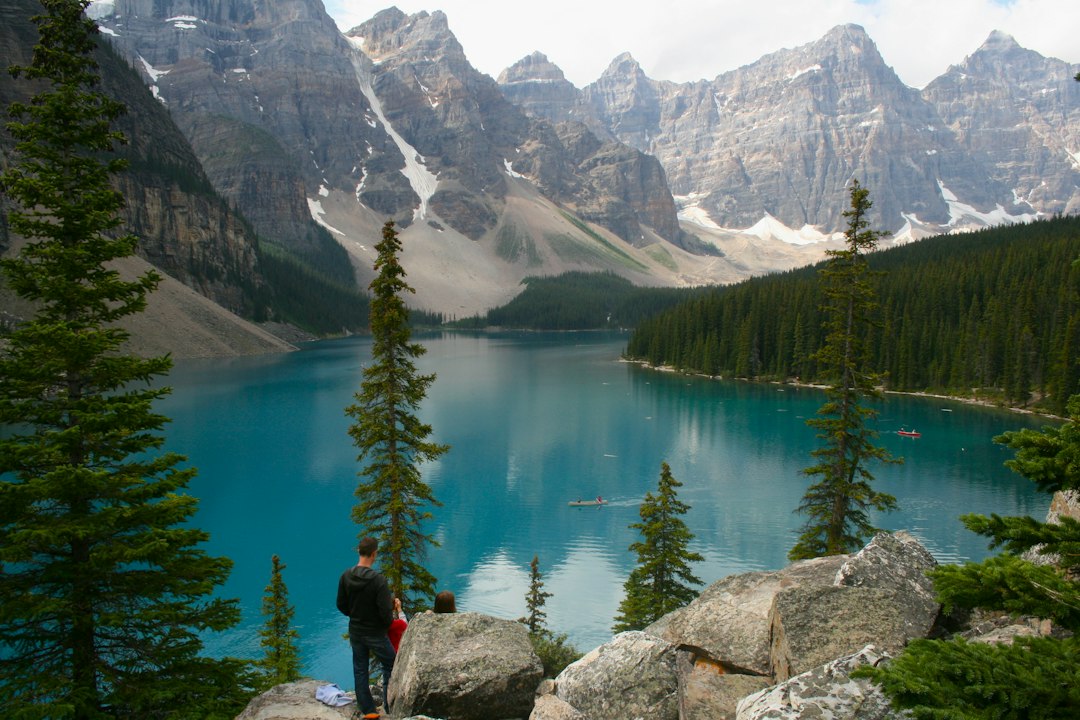 A person views a vibrant blue lake and majestic mountains