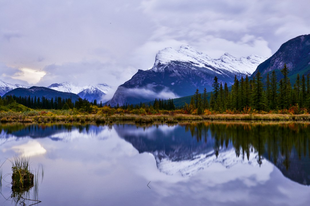 A lake surrounded by mountains and trees under a cloudy sky